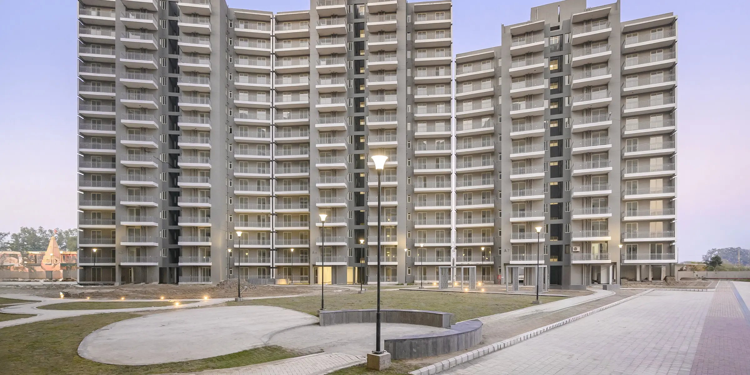 Completed residential towers and central open space at Smart Homes Karnal, dusk.
