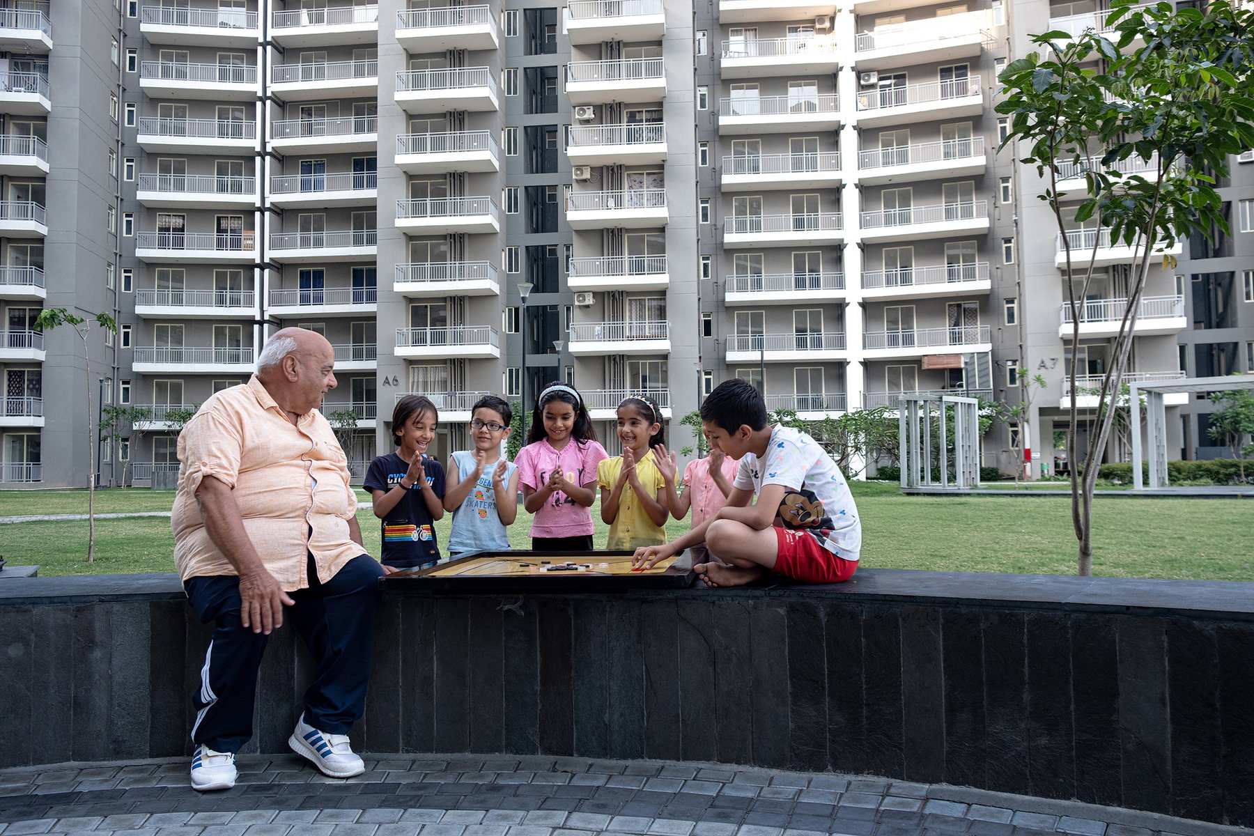 Residents gathered around a game in the courtyard at Smart Homes Karnal.