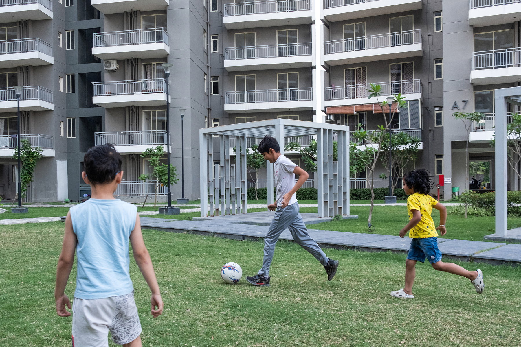 Children playing football on a shared lawn at Smart Homes Karnal.